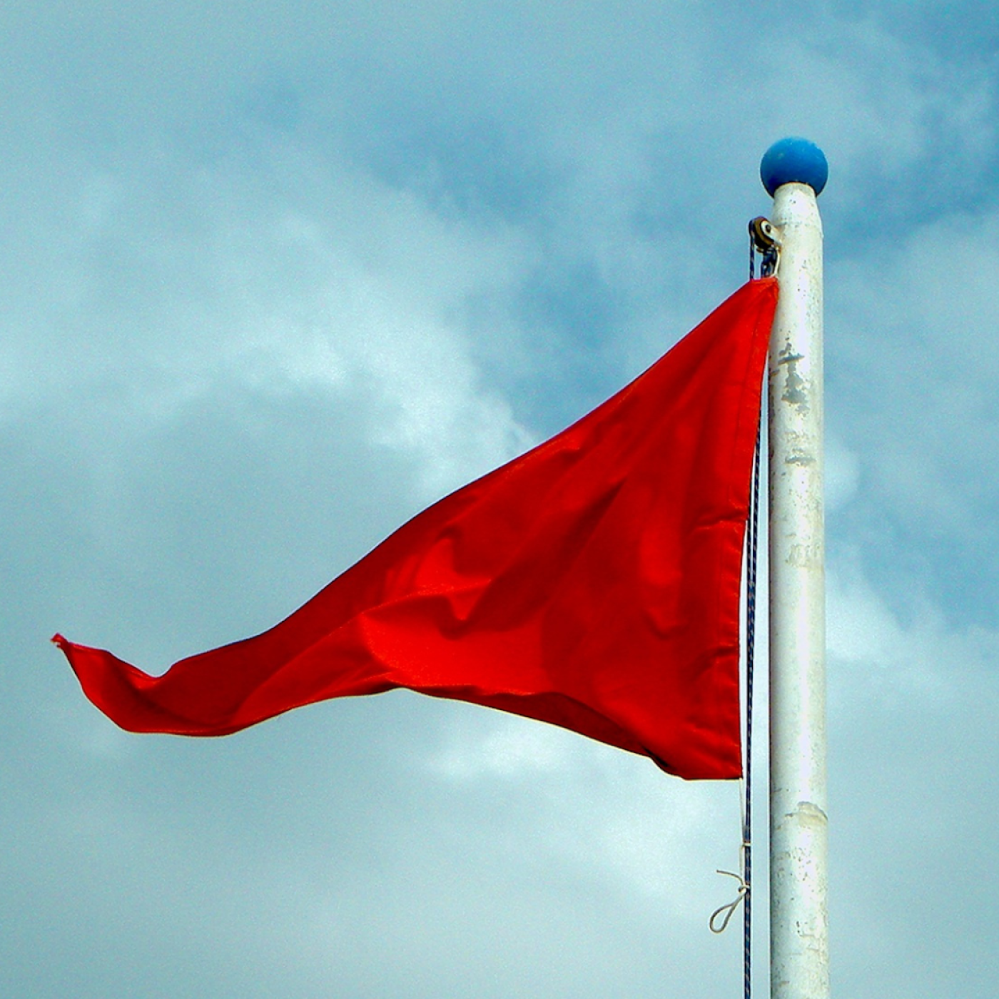 red flag on cloudy background.